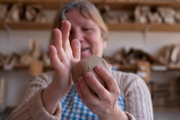 Female hands holding a ball made of clay to start working on the wheel