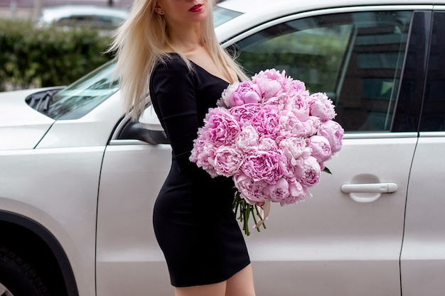 Female hands holding beautiful bouquet of pink peonies