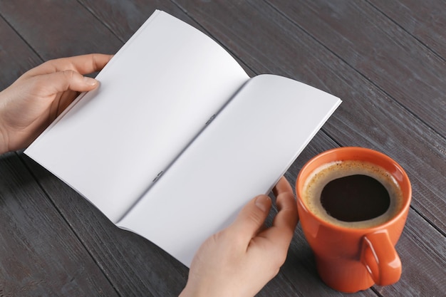 Female hands holding blank brochure on wooden background