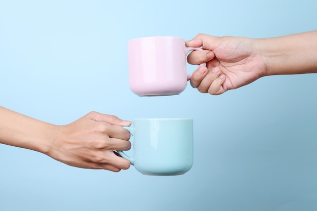 Photo female hands holding blue and pink cup hot coffee mockup isolated on blue background