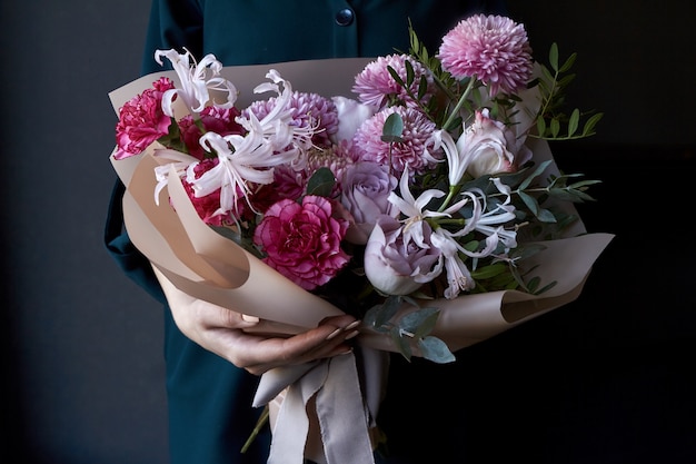 Female hands holding a bouquet decorated in vintage style on a dark background