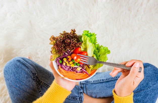 Mani femminili che tengono ciotola con insalata di lattuga verde