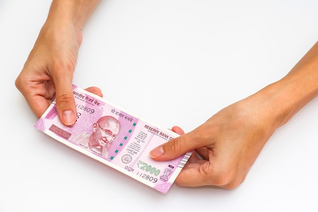 Female hands holding brand new 2000 indian rupees banknotes.