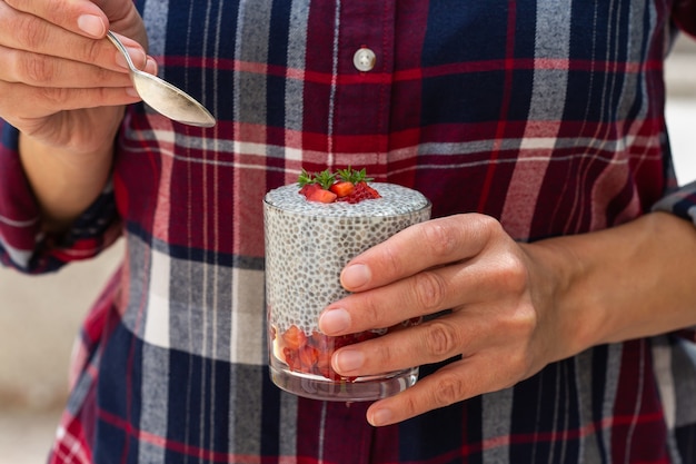 Female hands holding chia pudding with fresh strawberries for breakfast