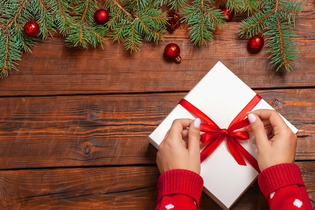 Mani femminili che tengono un contenitore di regalo di natale