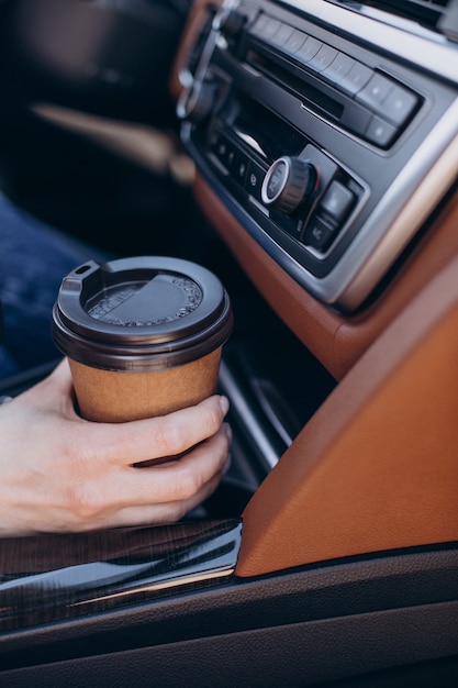 Female hands holding coffee cup in the car