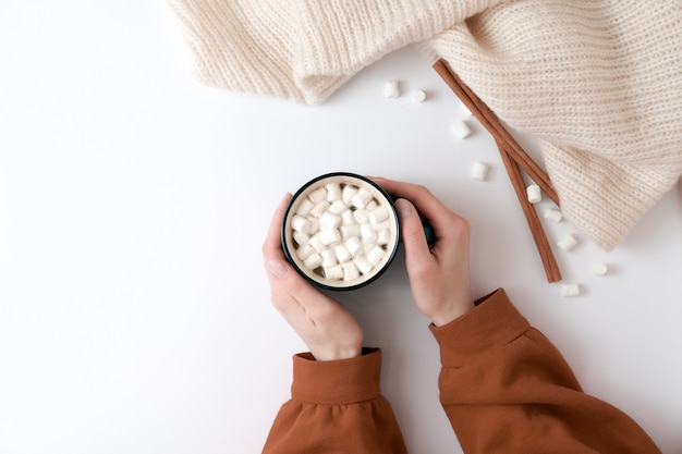 Mani femminili che tengono tazza di cioccolata calda con marshmallow