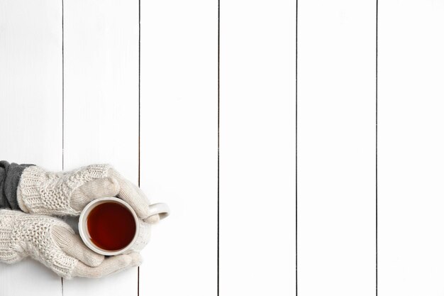 Female hands holding cup of hot drink on wooden table background