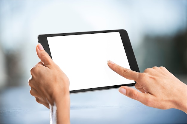 Female hands holding digital tablet with white screen on blurred background