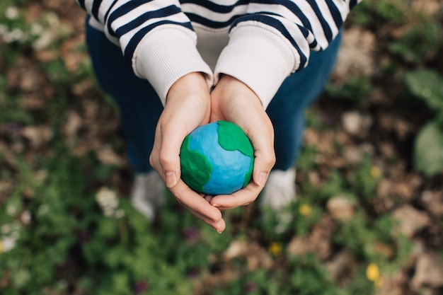 Female hands holding Earth against green spring background.