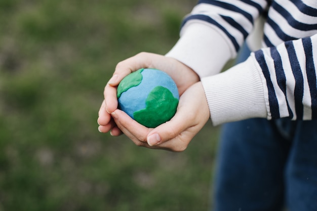 Female hands holding Earth against green spring background.