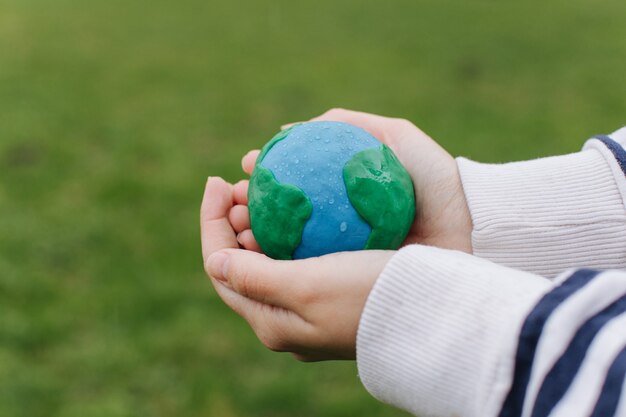 Female hands holding Earth against green spring background.