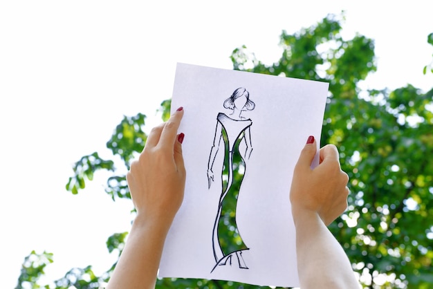 Female hands holding fashion sketch outdoors