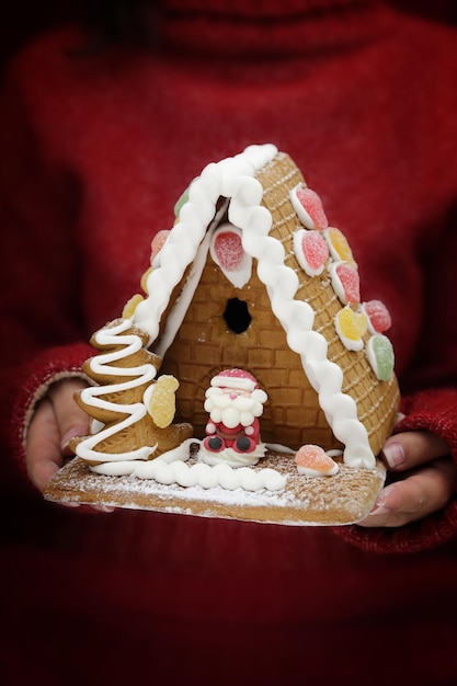 Female hands holding festive gingerbread house