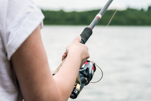 Female hands holding a fishing rod and twist the handle