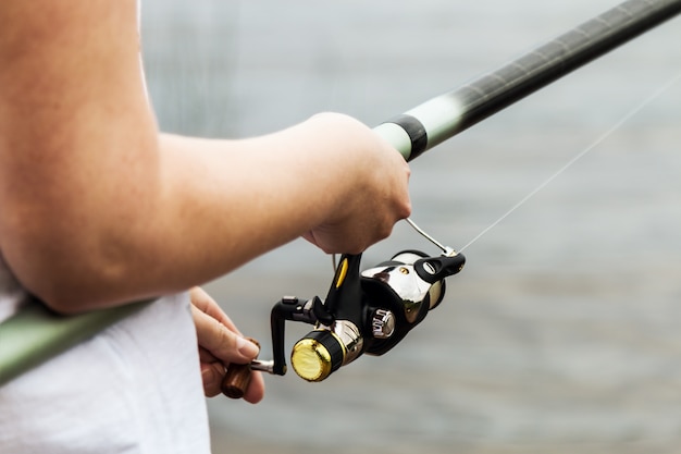 Mani femminili che tengono una canna da pesca