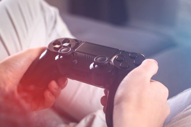 Mani femminili che tengono il controller di gioco. concetto di streaming e giochi moderni con una grande tv seduta a casa sul divano, foto per il tempo libero