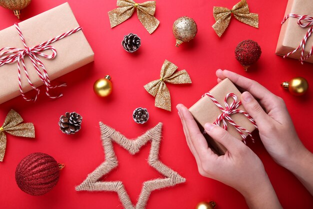 female hands holding gift box on a red background