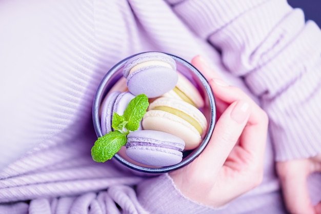 Female hands holding glass with lavender and lemon macaroons