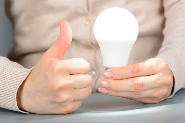 Mani femminili che tengono una luce led incandescente e mostrano come