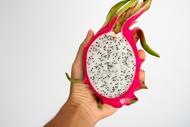 Female hands holding a half of the ripe white dragon fruit on white background