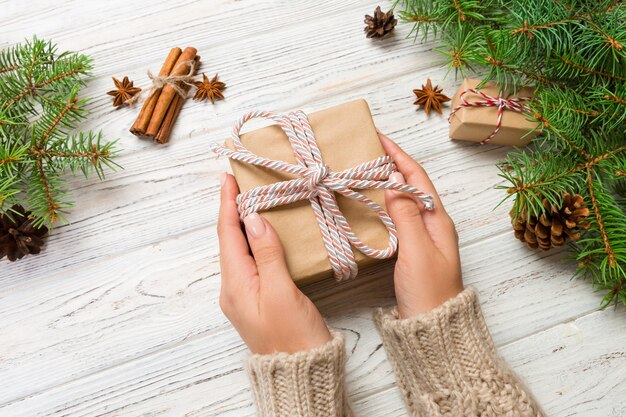 Female hands holding handmade present box in recycled paper with Christmas decoration