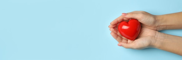 Female hands holding heart on blue