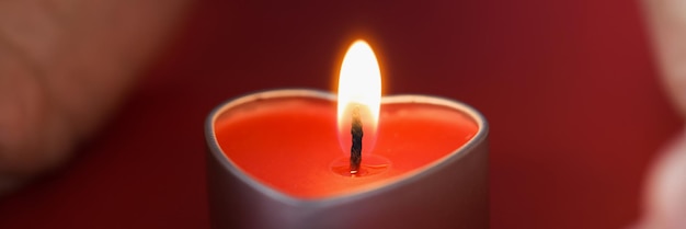 Female hands holding a heart shaped candle in dark night candlelight divination concept