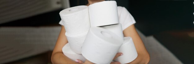 Женские руки, держа много рулонов белой туалетной бумаги крупным планом