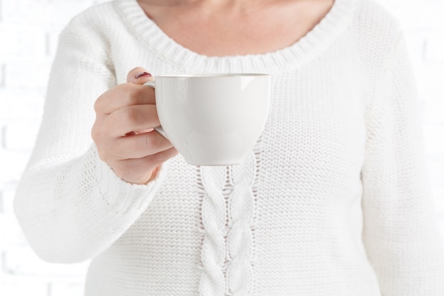 Mani femminili che tengono una tazza di tè caldo