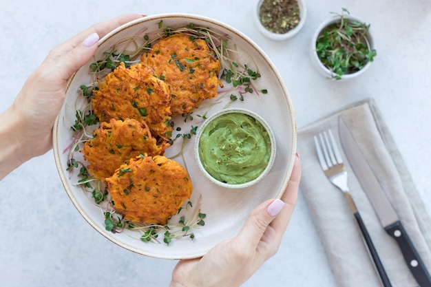 Female hands holding plate with vegan sweet potato fritters