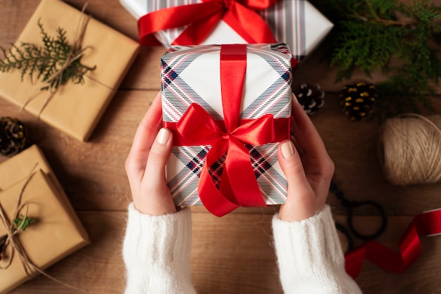 Female hands holding present with red bow on rustic . Festive backdrop for winter holidays.