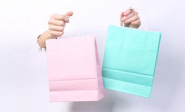 Female hands holding shopping bags through torn hole white paper