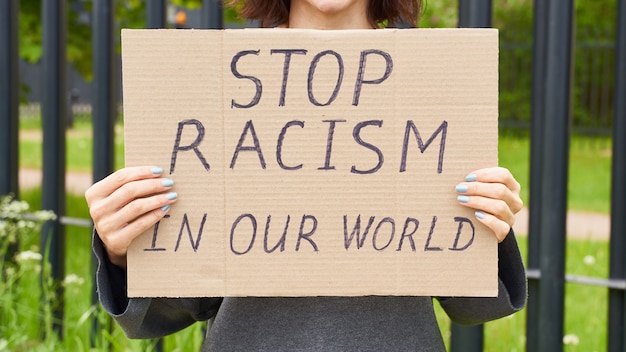 Female hands holding a sign about racism
