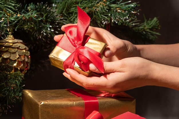 Female hands holding small new year present with red bow