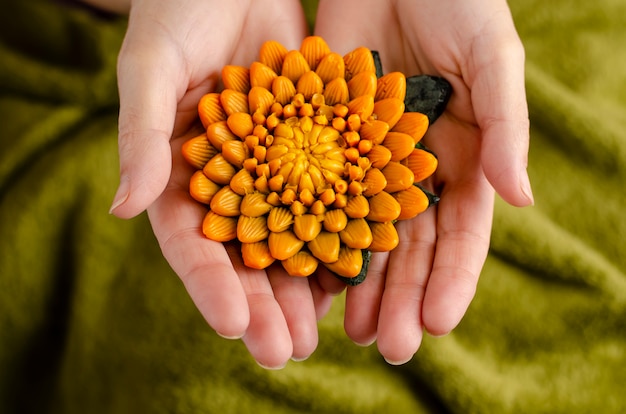 Mani femminili che tengono un sapone a forma di fiore di crisantemo.