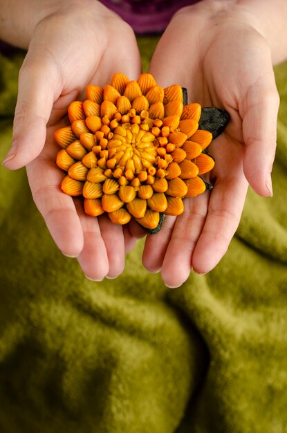 Женские руки, держа мыло в форме цветка хризантемы.