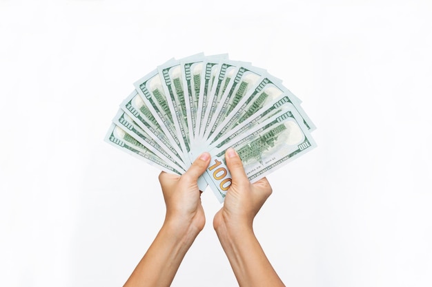 Female hands holding a stack of hundred-dollar cash bills on a white background. Money, wealth