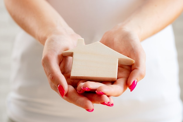 Female hands holding toy wooden house miniature close up