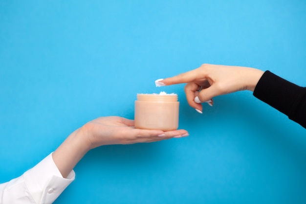 Female hands holding and trying cream from jar