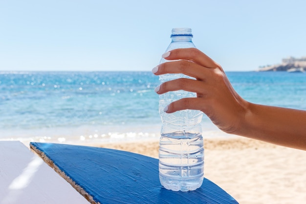 ビーチで水のボトルを保持している女性の手