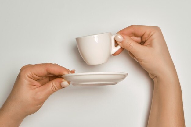 Female hands holding a white coffee cup and saucer on a white background concept Banner design