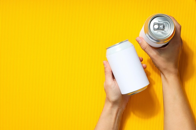 Female hands holds blank cans on yellow textured background