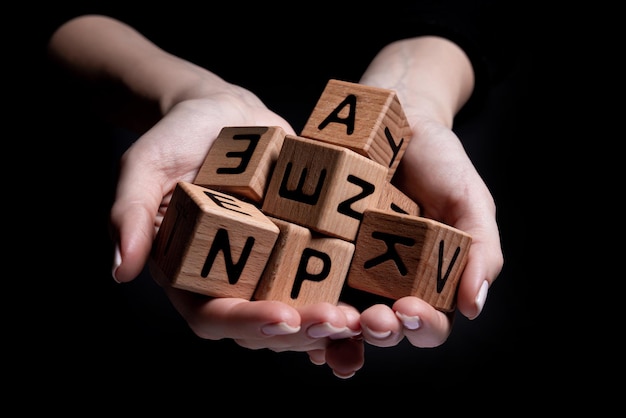 Female hands holds a cube with letters isolated on black