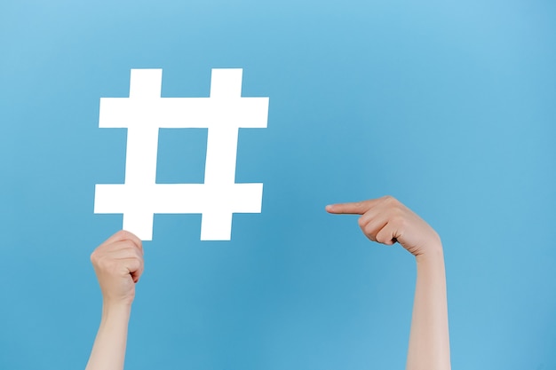 Photo female hands holds large big white hashtag sign