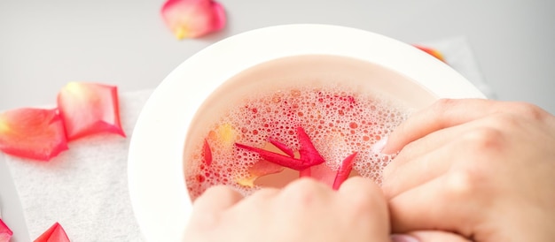 사진 스파에서 장미 꽃의 분홍색 꽃잎과 함께 물 그릇에 여성 손