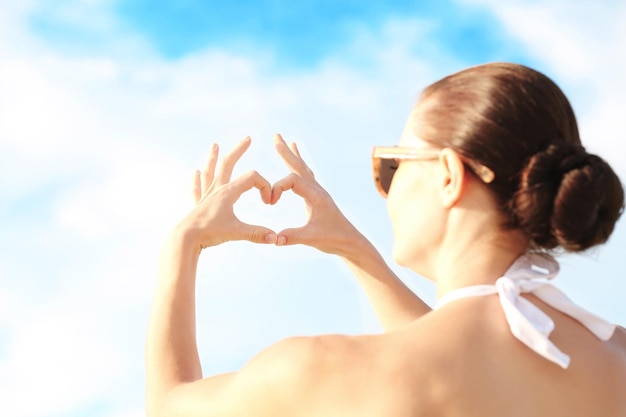 写真 空の背景にハート形の女性の手