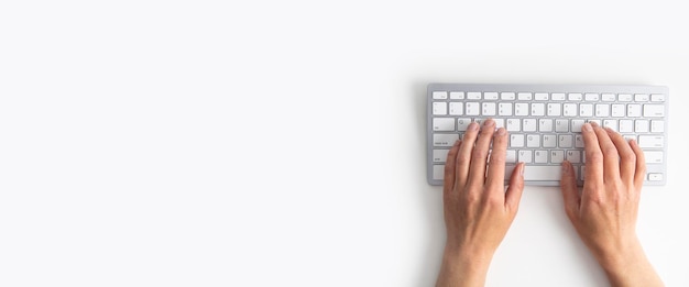 白い背景の上のキーボードの女性の手上面図フラットレイバナー