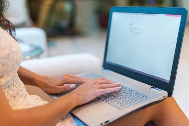 Female hands on keyboard with opened web page in browser at screen Cropped image of woman surfing the internet her laptop