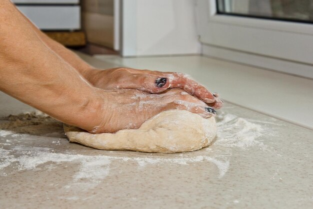 写真 女性の手は,白いキッチンテーブルで粉と面粉を混ぜます.トップビューの焼き付け準備段階の調理